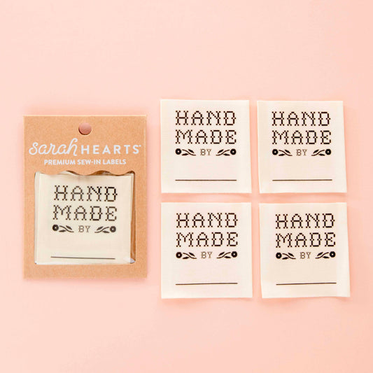 Set of 'Hand Made by' labels with packaging on a pink background