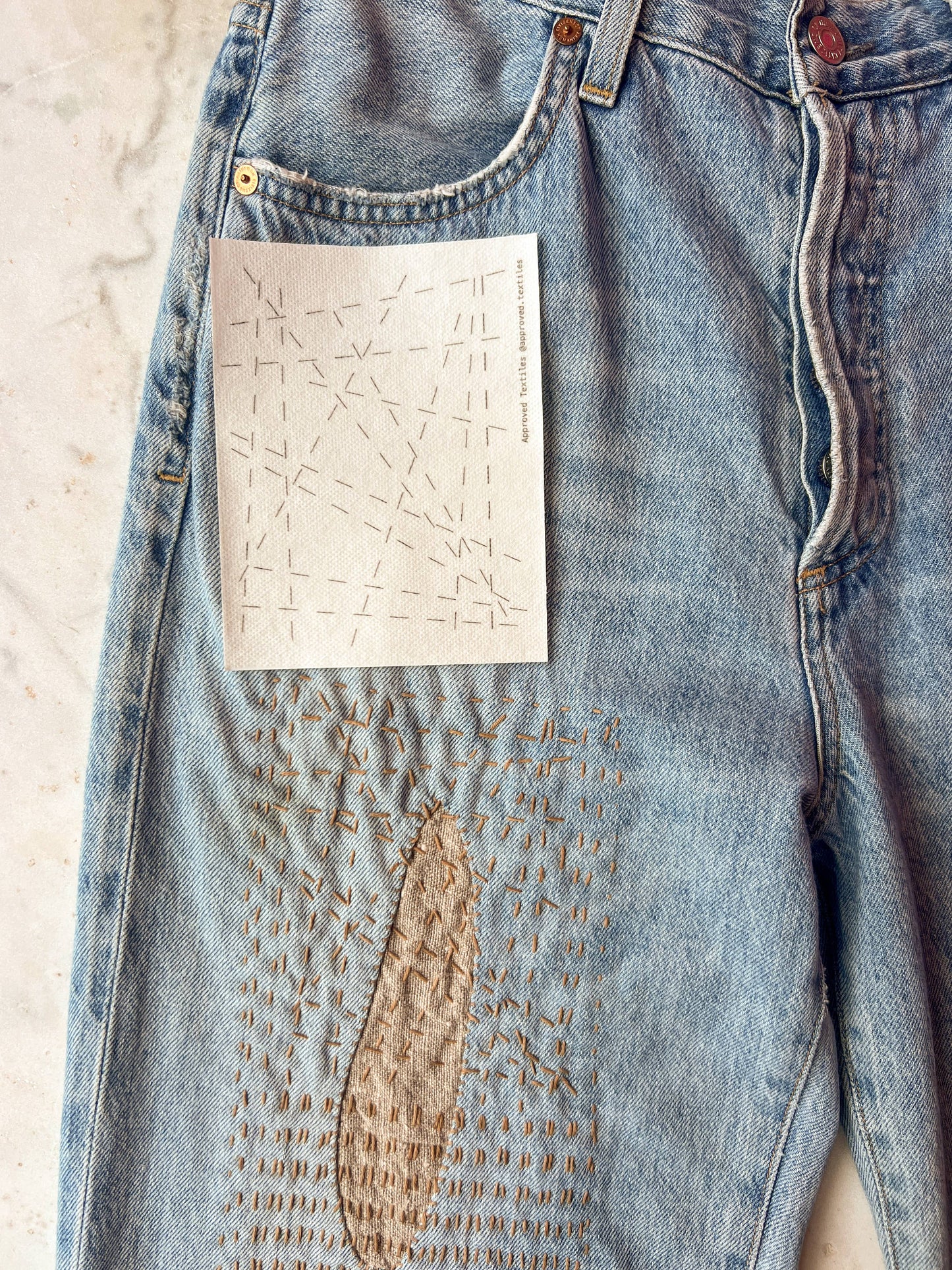 Denim jeans with a large patch on a light background