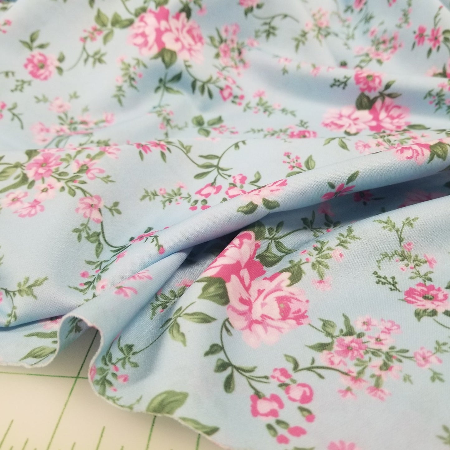 Floral fabric with pink flowers and green leaves on a light blue background.