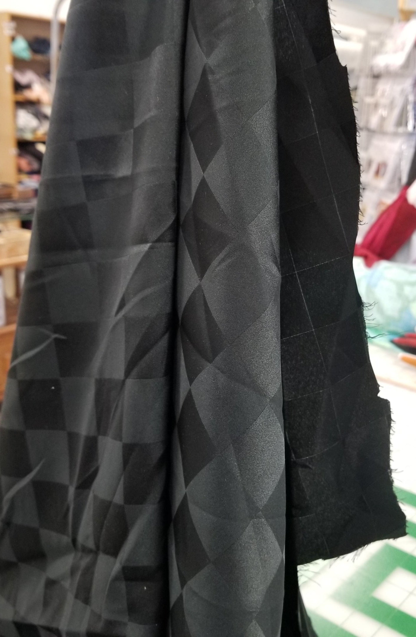 Close-up of black quilted jacket with blurred indoor background. Designer Deadstock fabric retail by the yard. LA Finch Fabrics