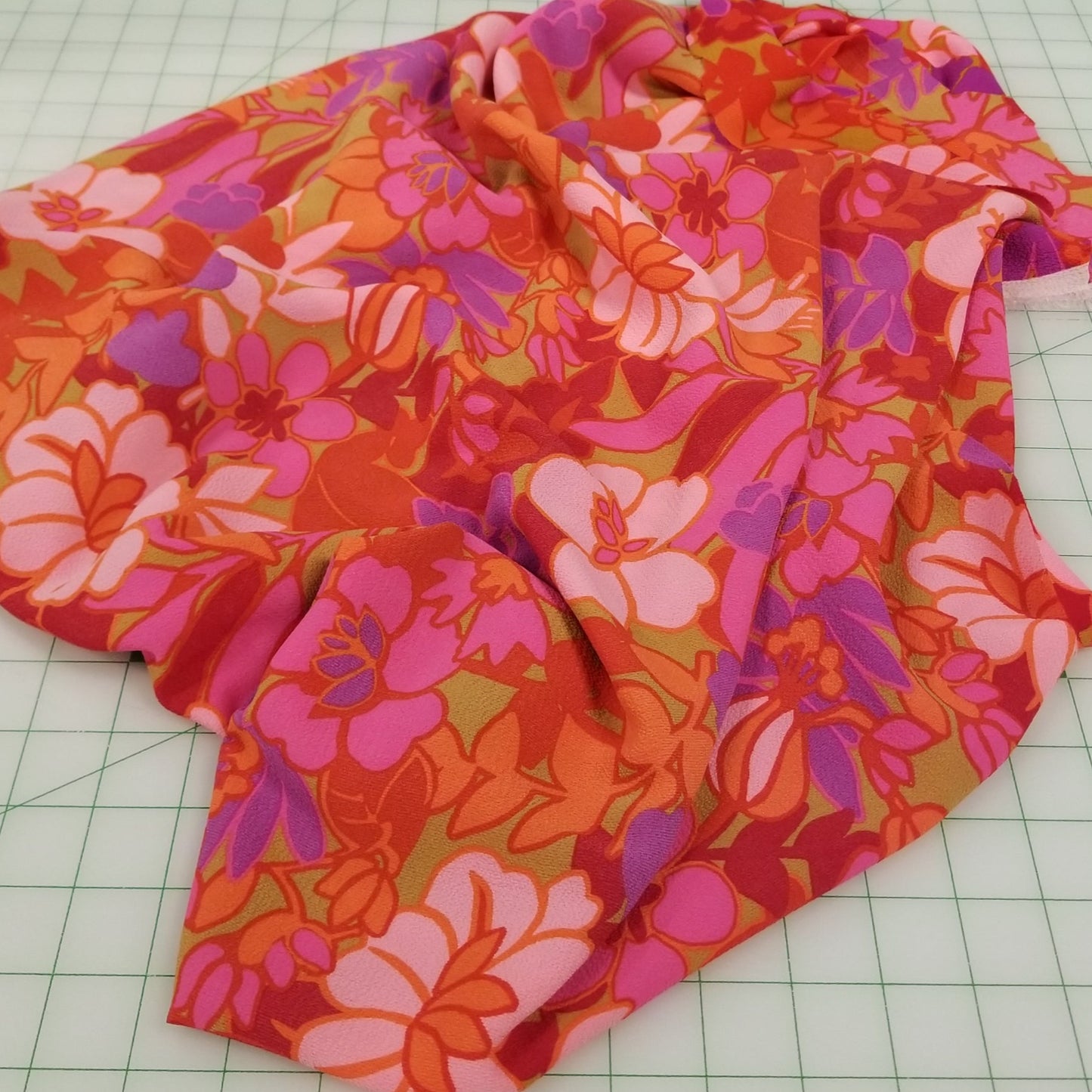 Floral fabric on a cutting mat with green fabric on the side. LA Finch Fabrics, Designer Deadstock Woven