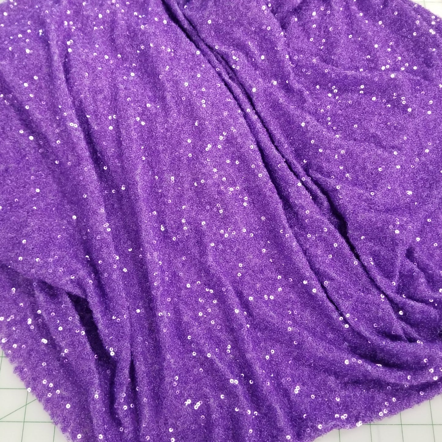Purple fabric with glitter on a cutting mat