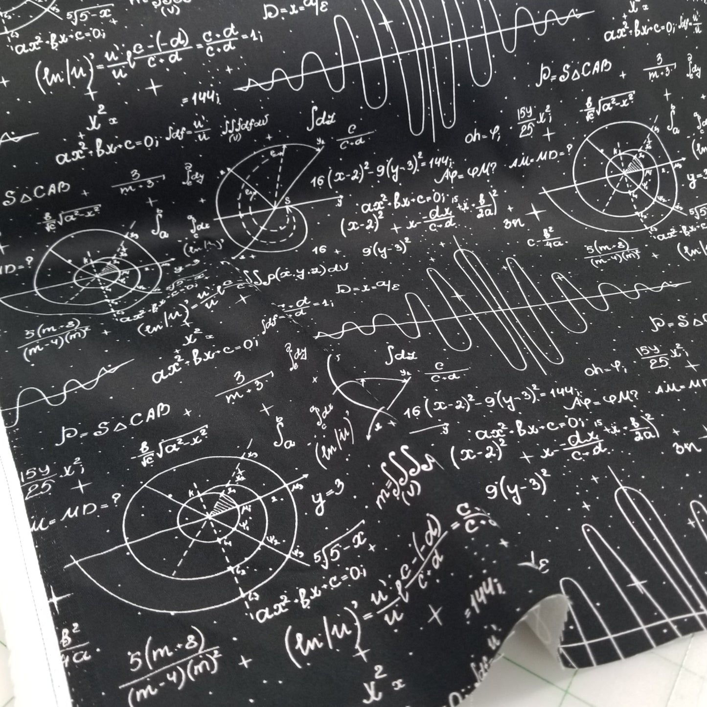 Black fabric with white mathematical equations and symbols on a white surface