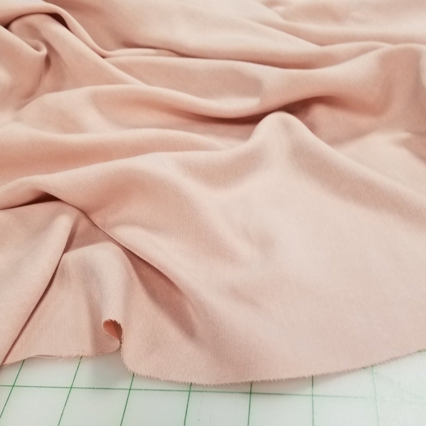 Pink fabric draped over a surface with a grid pattern in the background