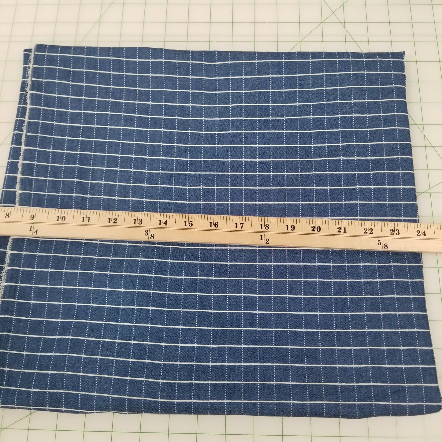 Blue checkered fabric with a ruler on a grid background