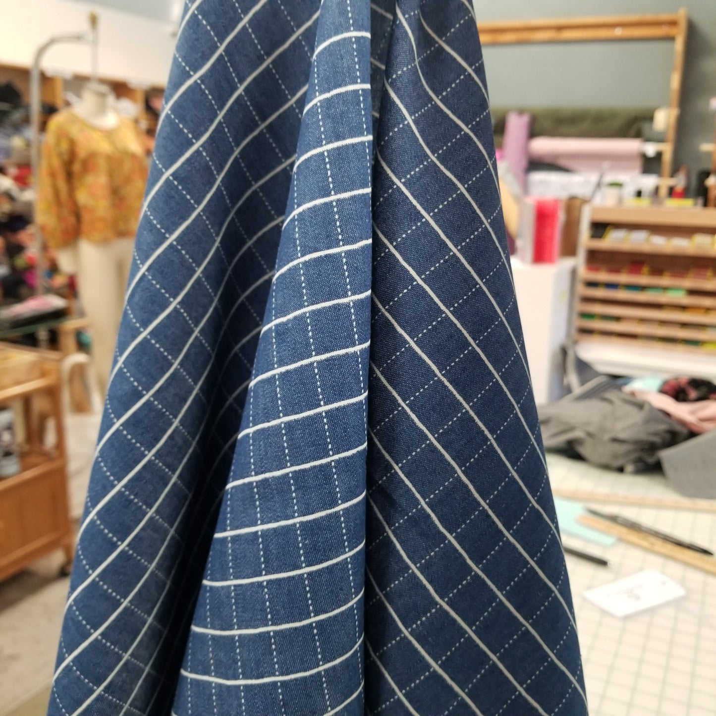 Roll of blue and white checkered fabric with a blurred indoor background