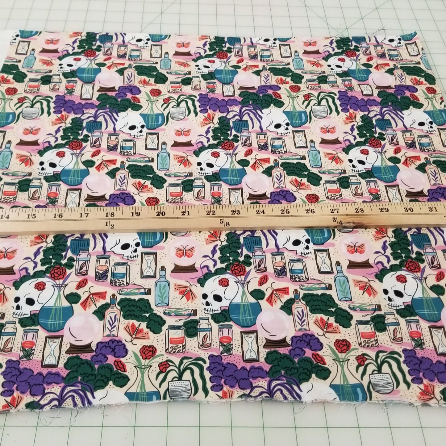 Fabric with a colorful pattern of cartoon characters and objects, measured by a ruler on a grid background.