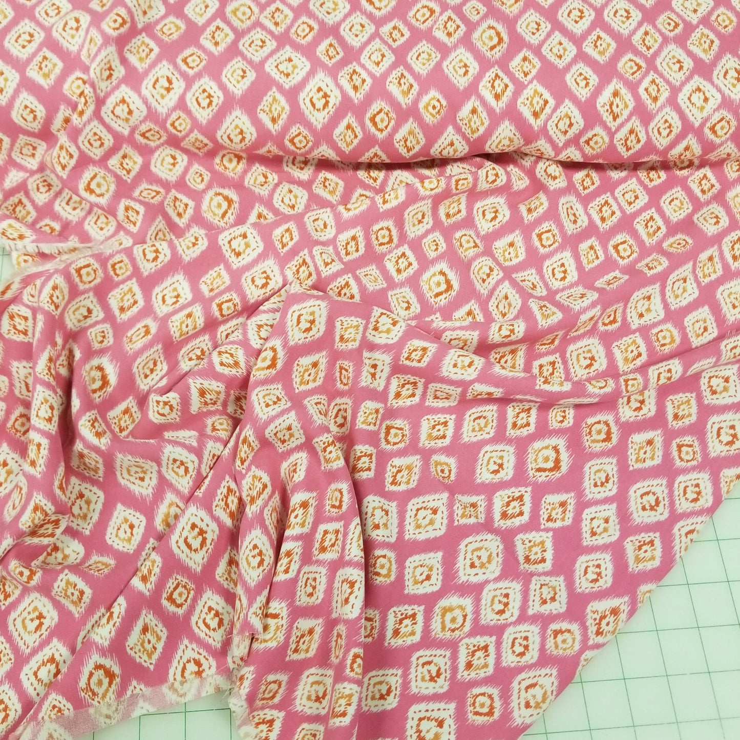 Pink fabric with a diamond pattern on a green cutting mat