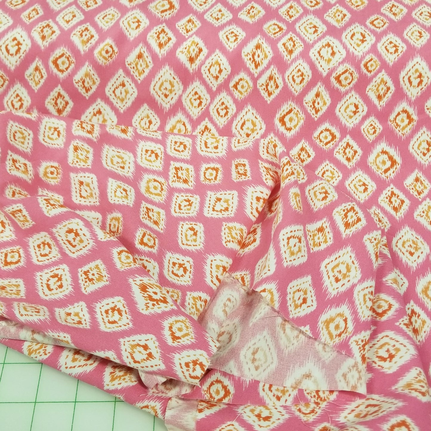 Pink fabric with a geometric pattern on a green cutting mat