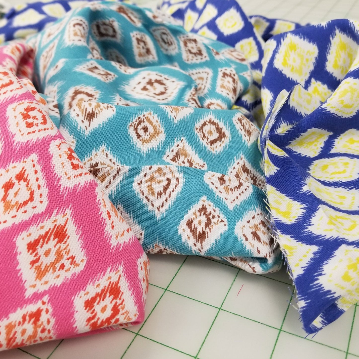 Three fabric samples with different patterns on a cutting mat.