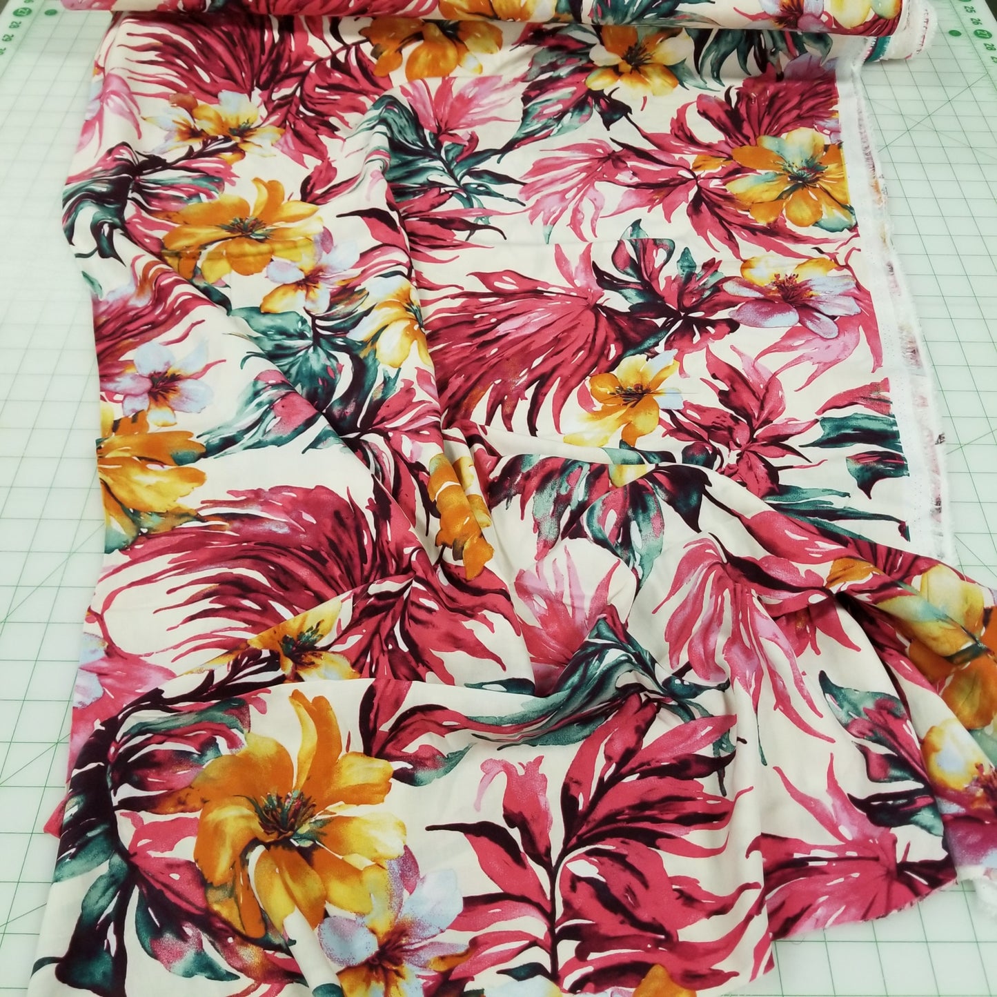Roll of fabric with colorful floral pattern on a tiled background