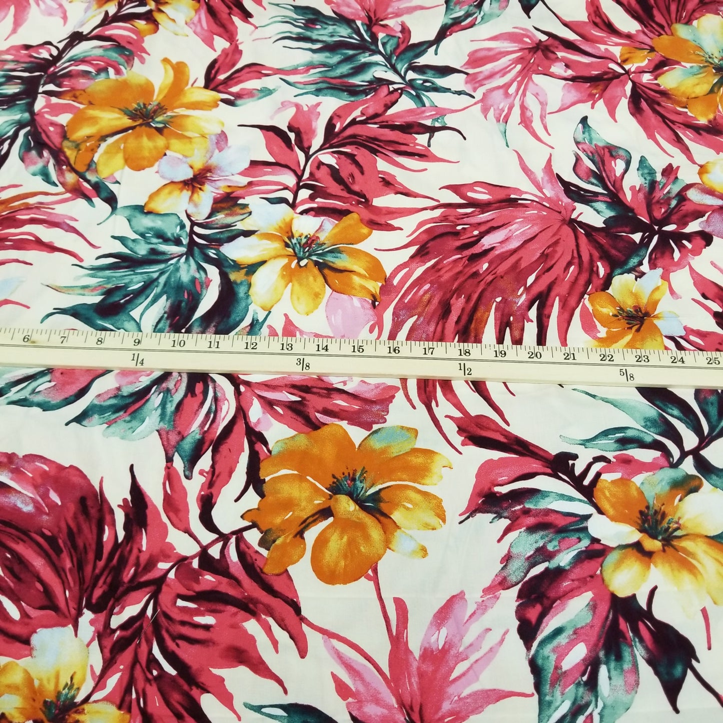 Floral fabric with pink leaves and yellow flowers on a white background, with a ruler for scale.