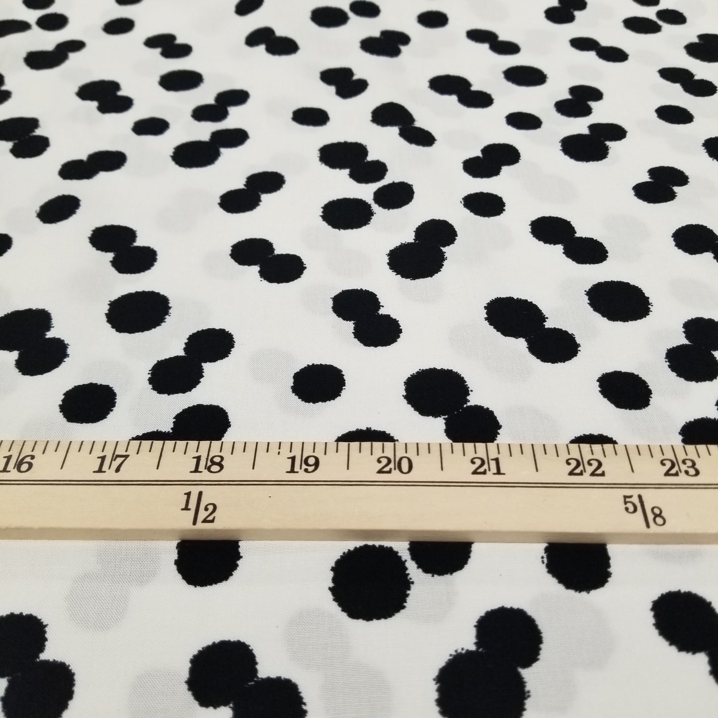 Black polka dots on a white background with a ruler for scale.