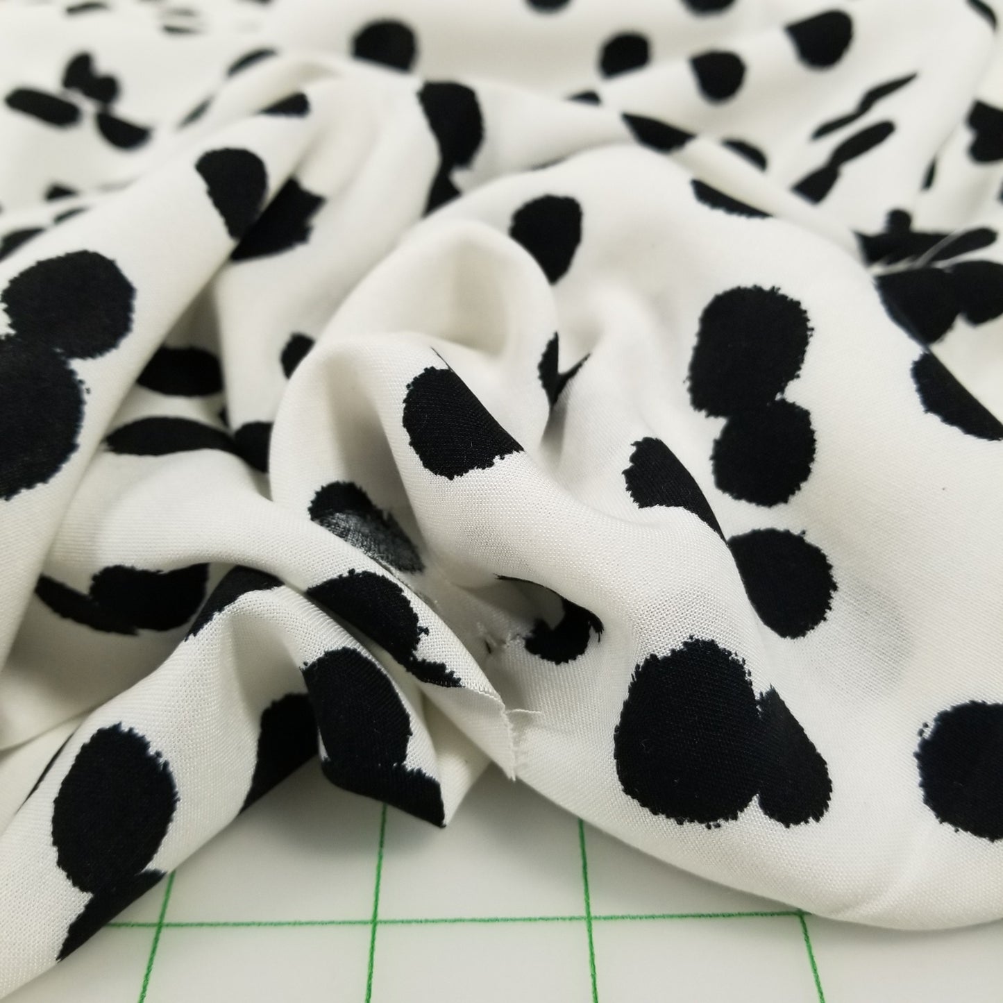 White fabric with black paw print pattern on a green grid background