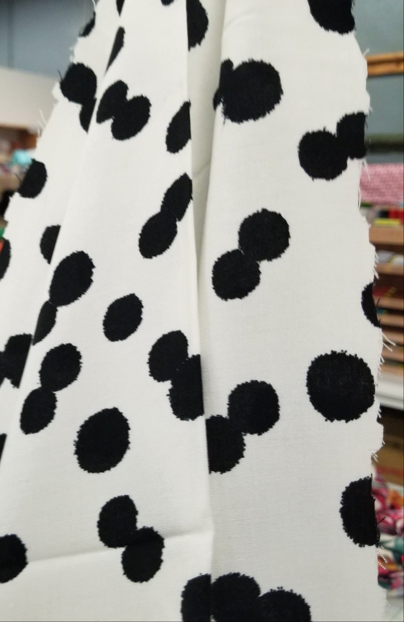 White fabric with black polka dots covering a blurred indoor setting.