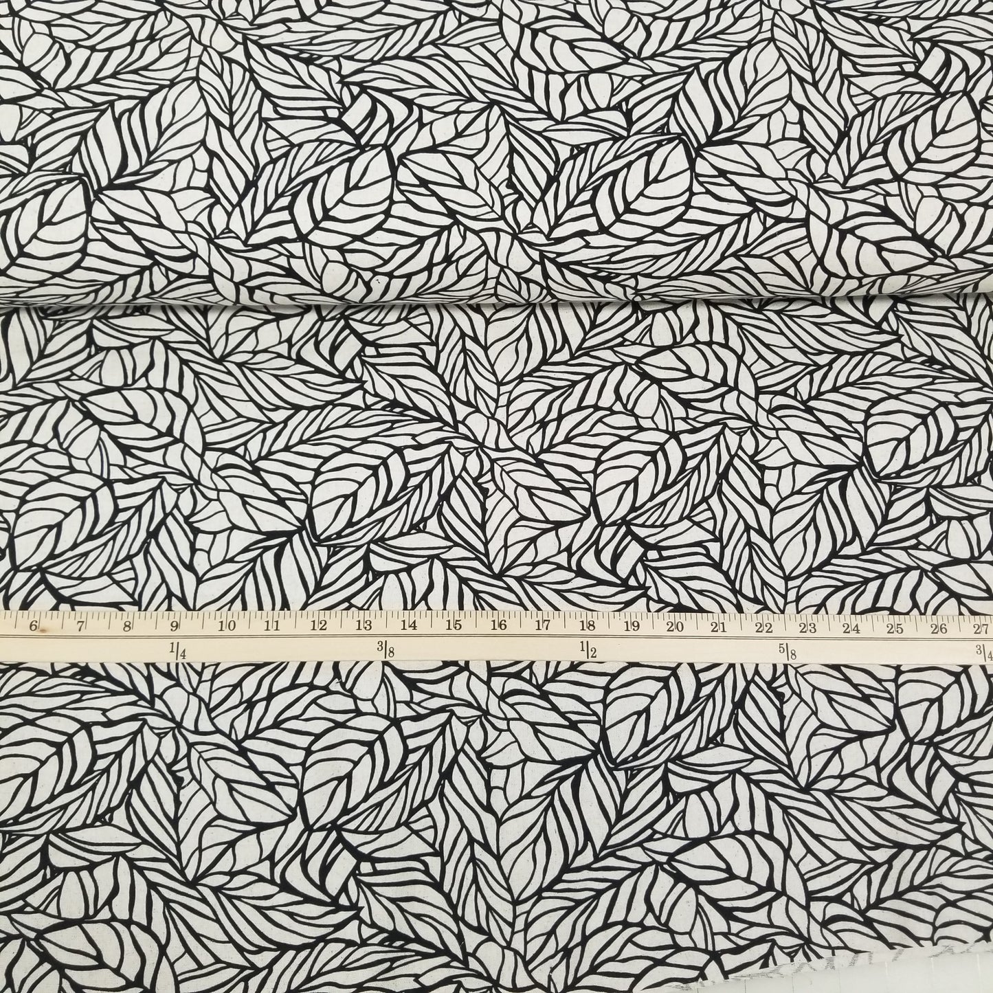 Fabric with black leaf pattern and a ruler for scale
