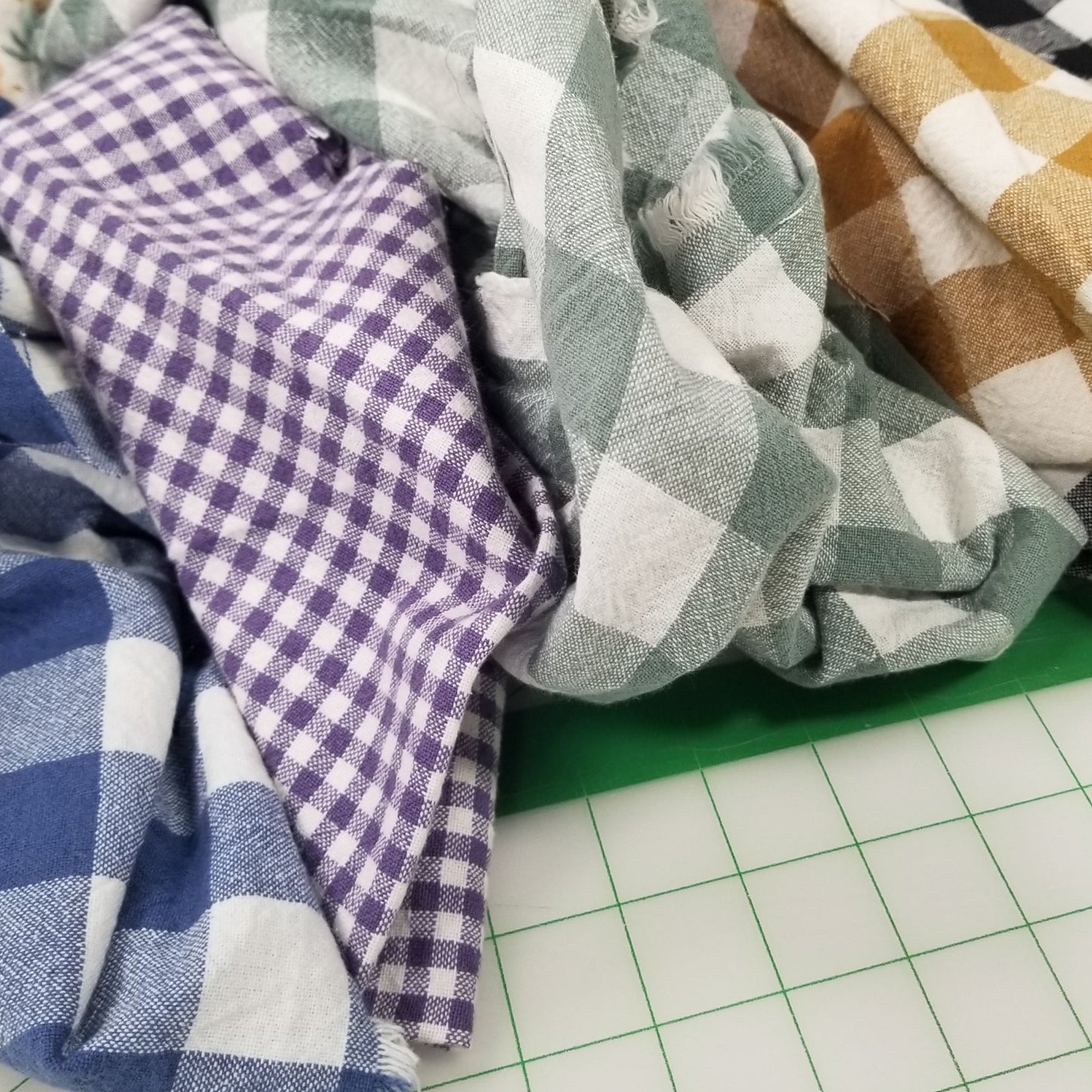Stack of folded fabric swatches in various patterns and colors on a grid background