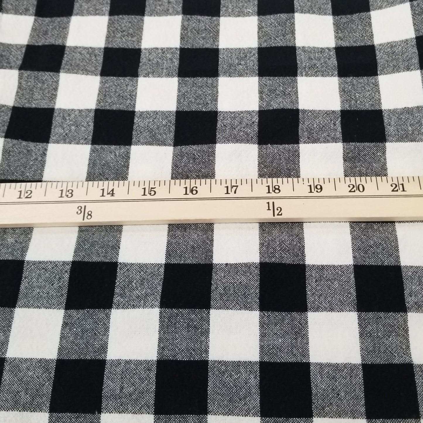 Black and white checkered fabric with a ruler on a grid background