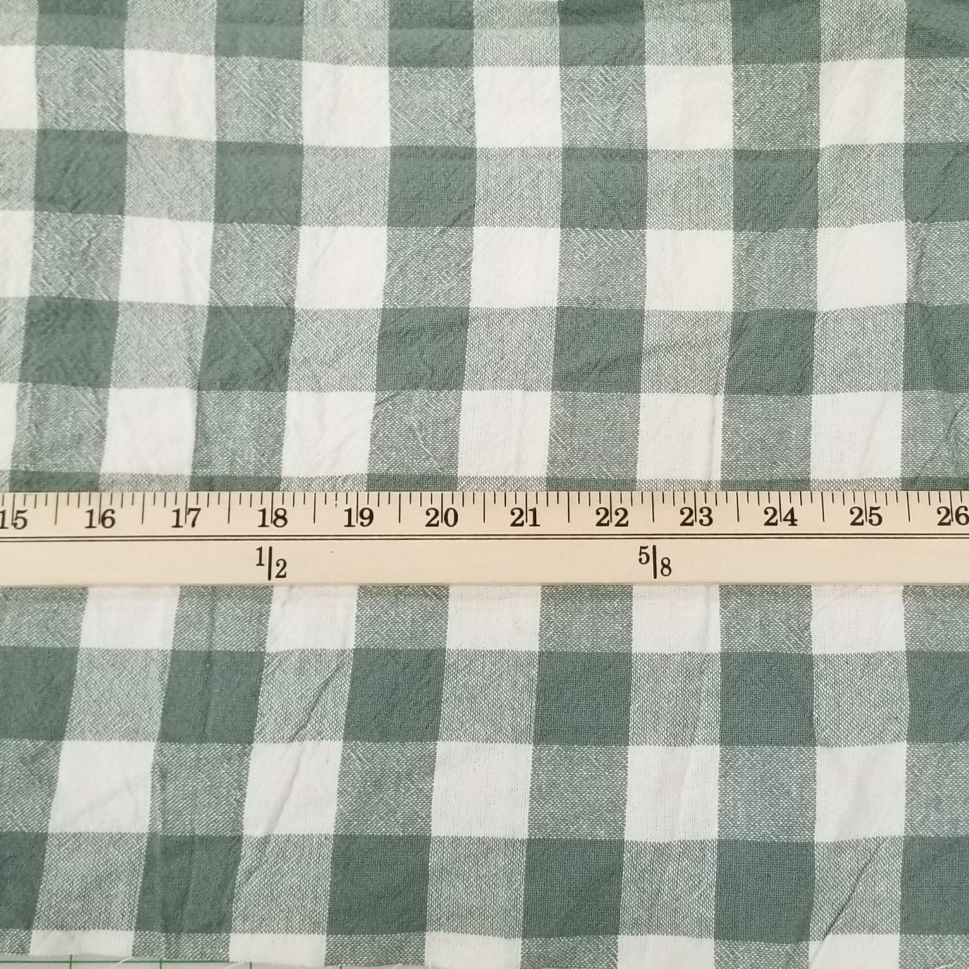 Green and white checkered fabric with a ruler on a grid background