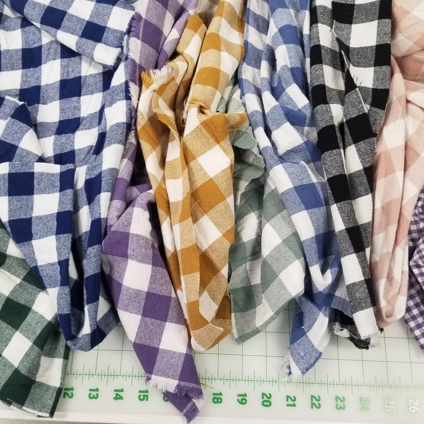 Stack of checkered fabrics with a ruler on a concrete surface