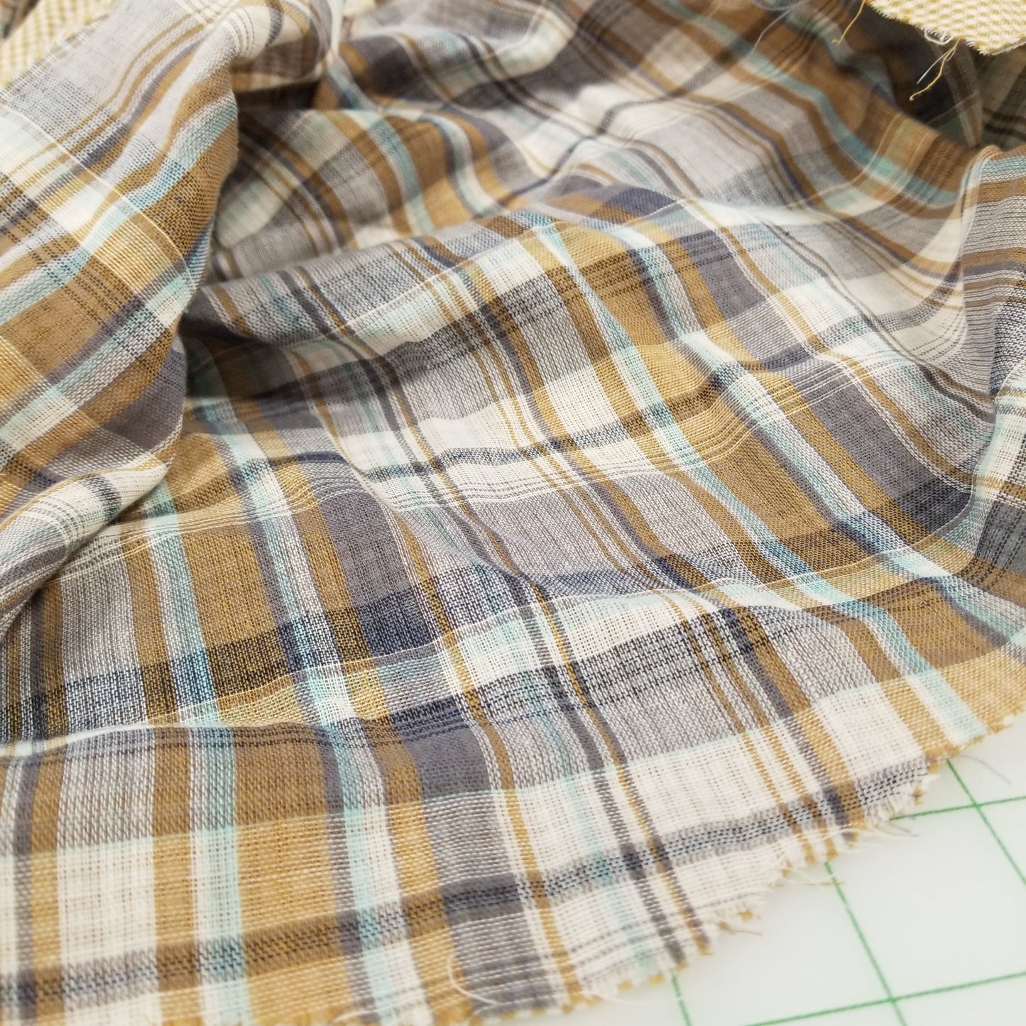 Close-up of plaid fabric with brown, blue, and beige colors on a grid background.
