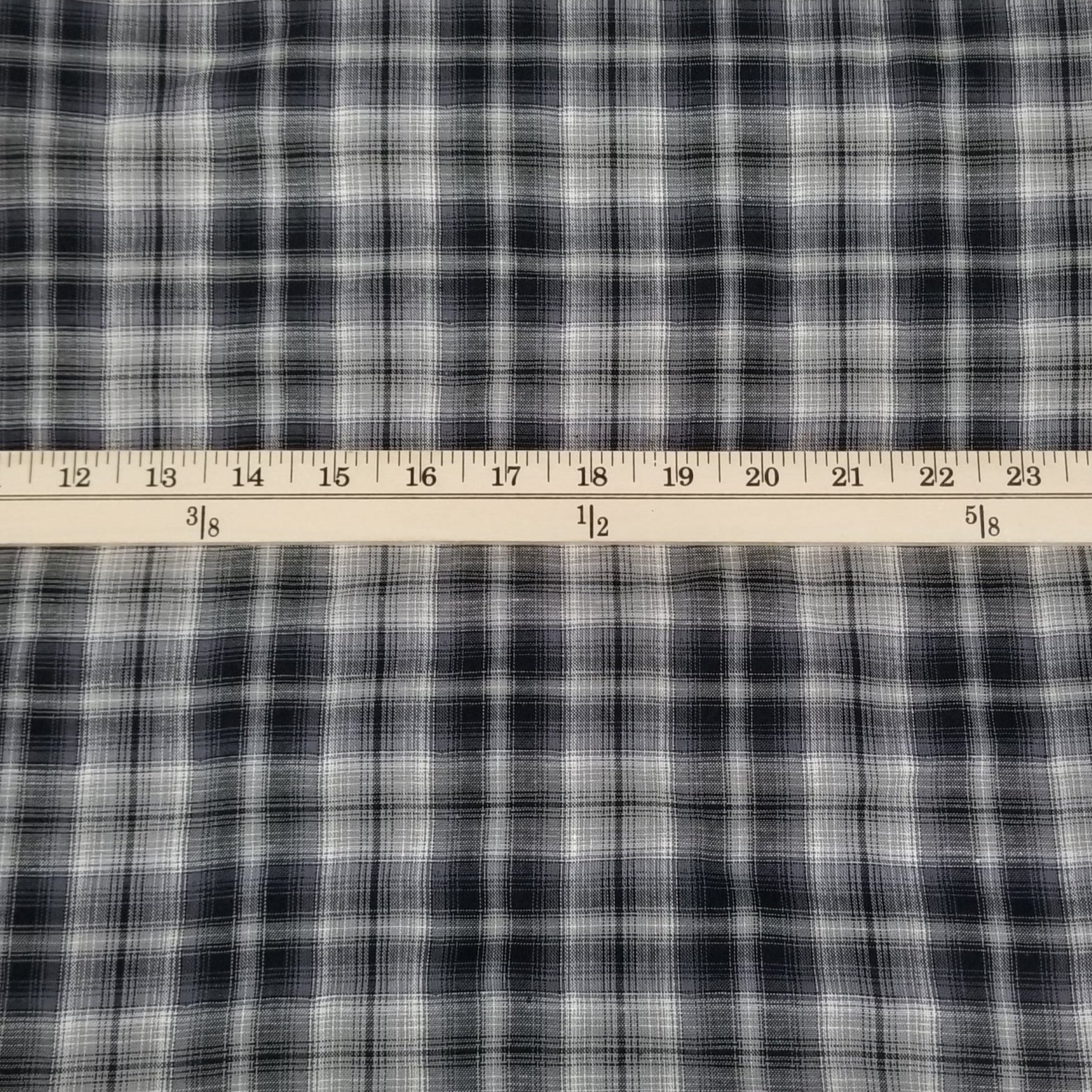 Black and white plaid fabric with a ruler for scale on a grid background