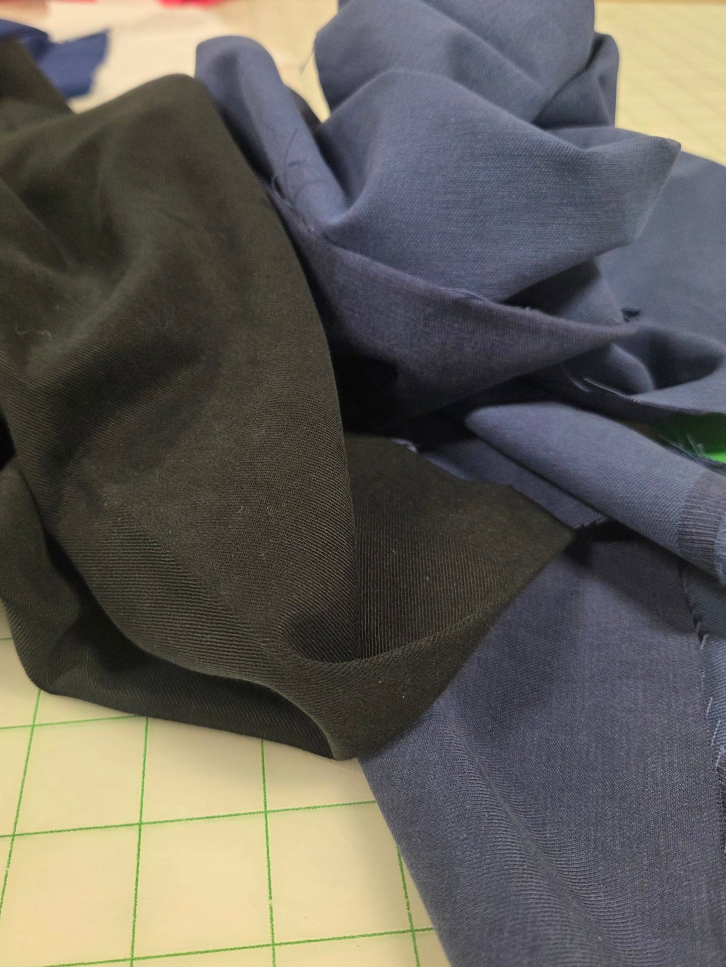 Stack of black and blue fabric on a grid surface. tencel cotton twill solids