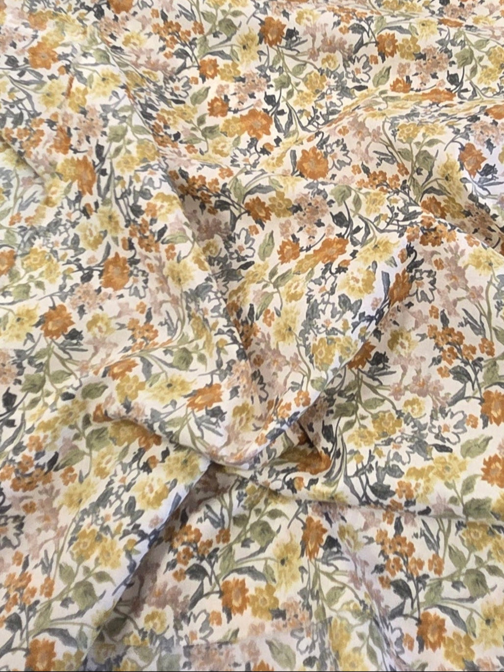 Floral-patterned fabric on a cutting mat with a ruler and measuring tape.
