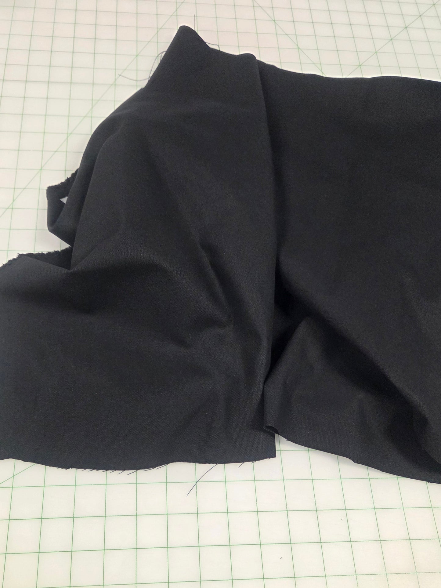 Folded black fabric on a grid surface, black canvas fabric sold by the yard