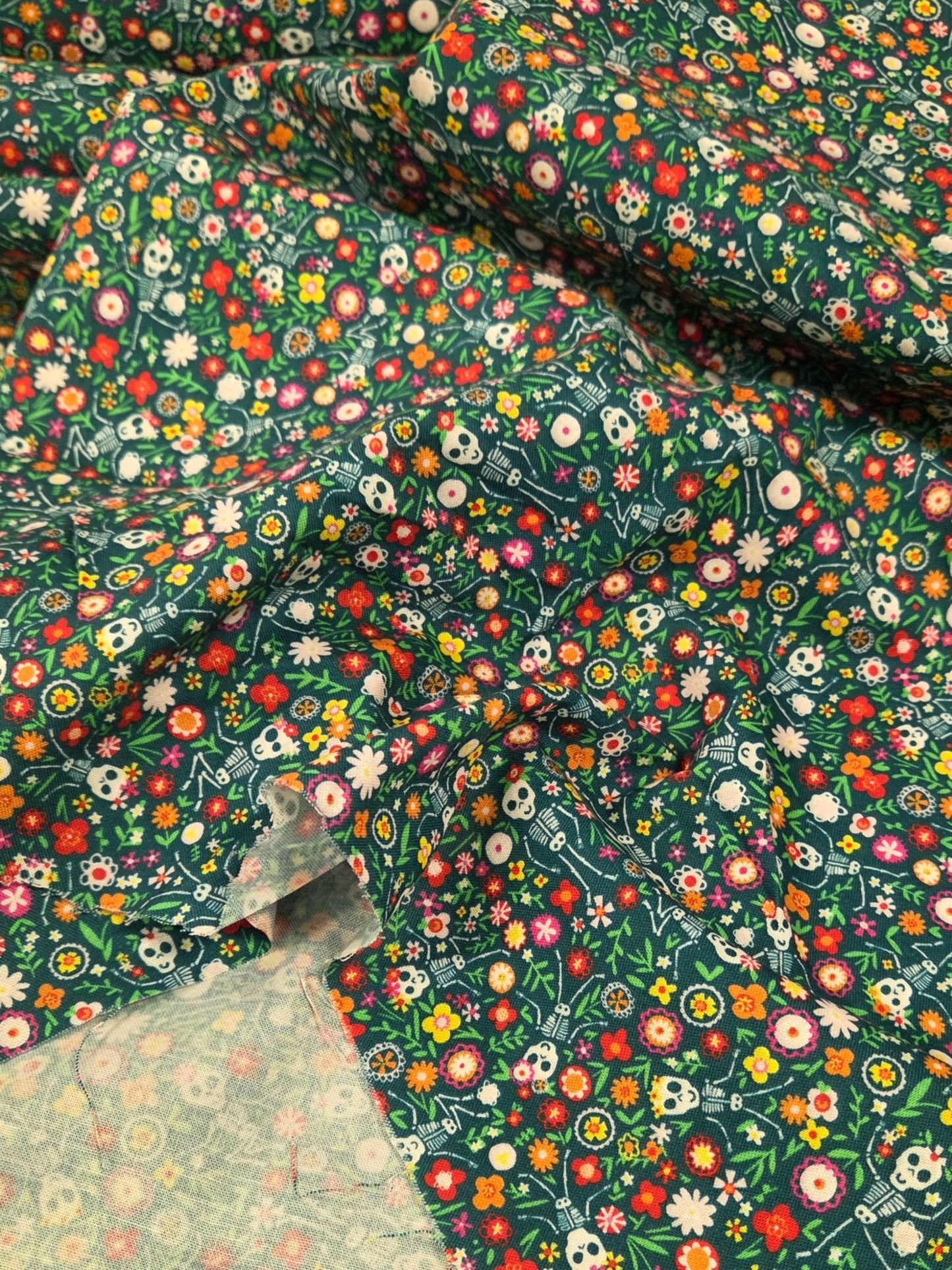 Close-up of floral fabric with a green background. Day of the Dead Fabric
