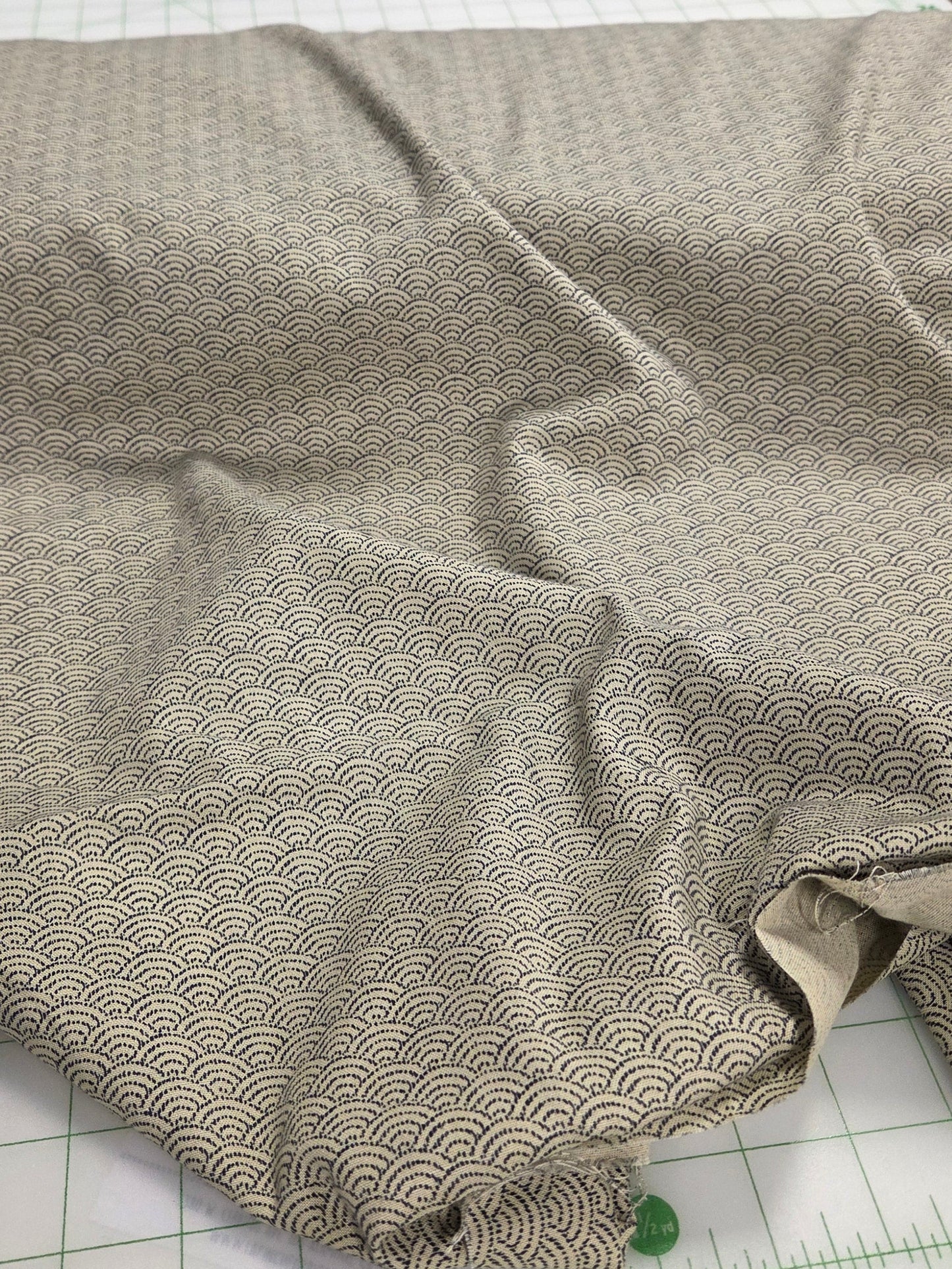 Fabric piece on a cutting mat with a ruler, scissors, and shelves in the background