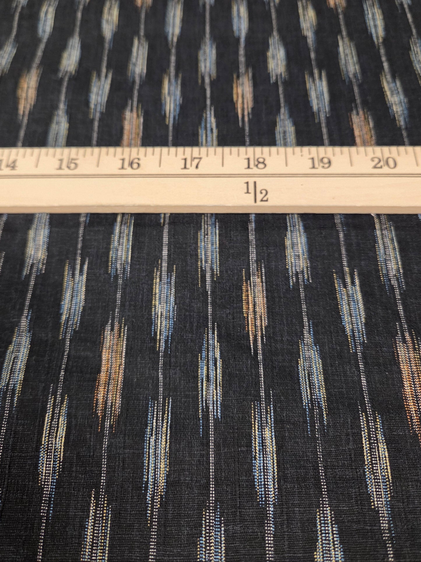 Fabric with a pattern and a ruler for scale on a grid background