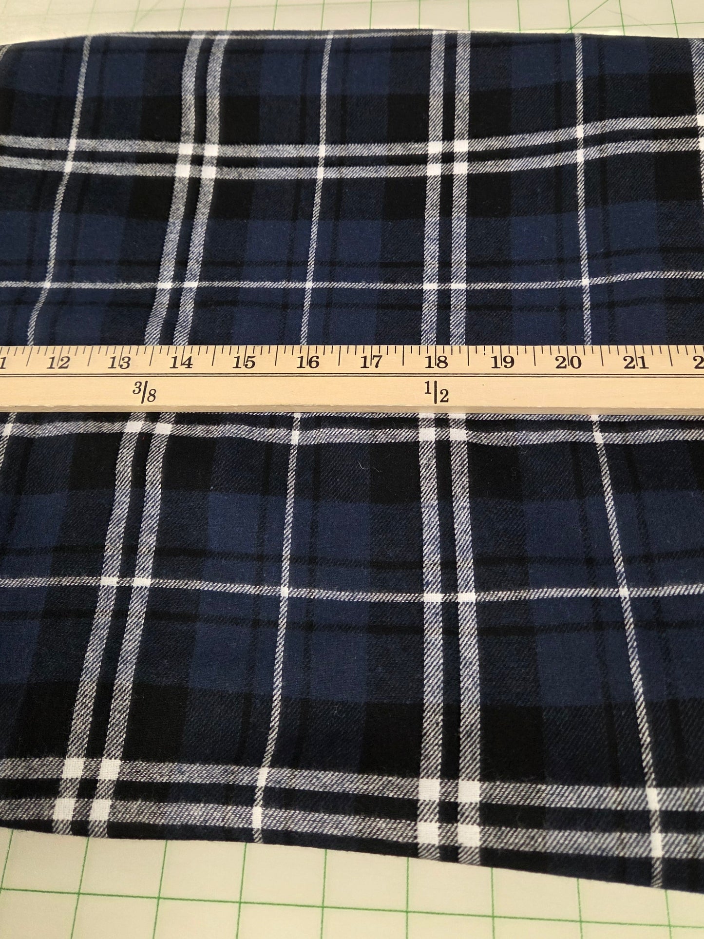 Plaid fabric with a ruler for scale on a grid background