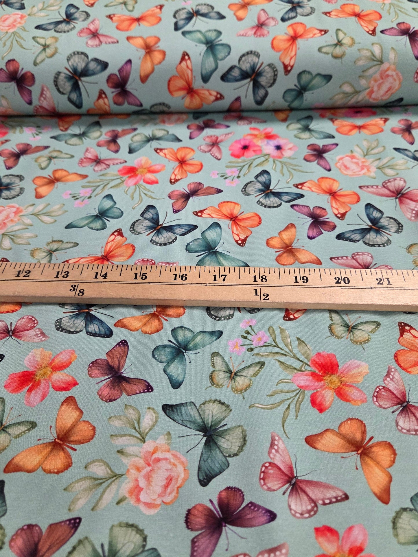 Butterfly and floral patterned fabric with a ruler for scale.