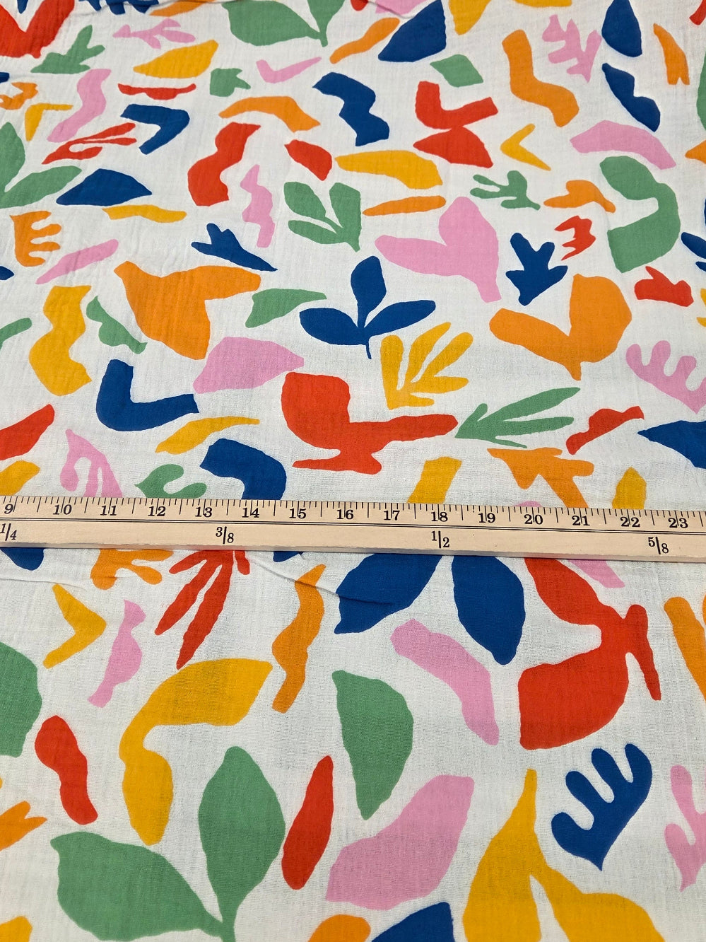 Colorful abstract patterned fabric with a ruler for scale on a white background