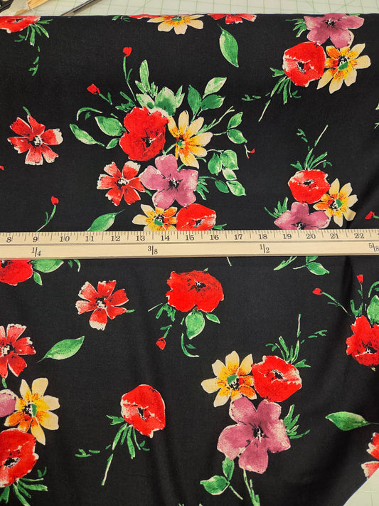 Floral fabric with red, yellow, and pink flowers on a black background, measured with a ruler.