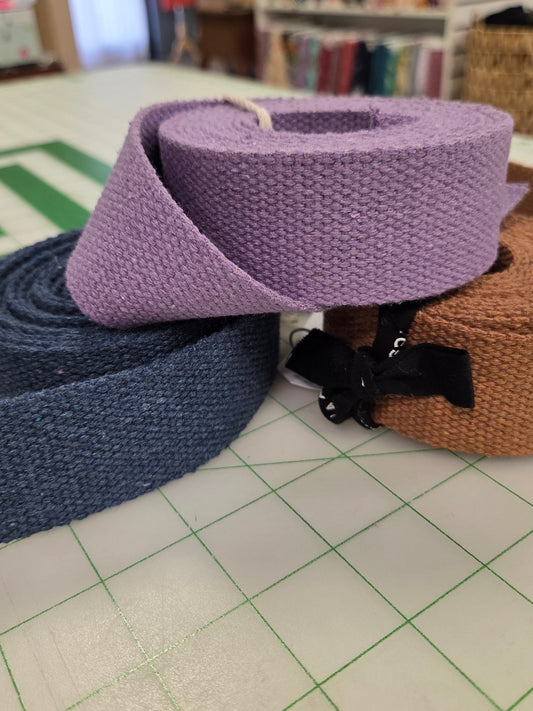 Purple and blue ribbons hanging on a hook with a bookshelf in the background.