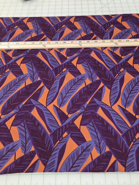 Fabric with purple and orange leaf pattern on a white grid background with measuring tape