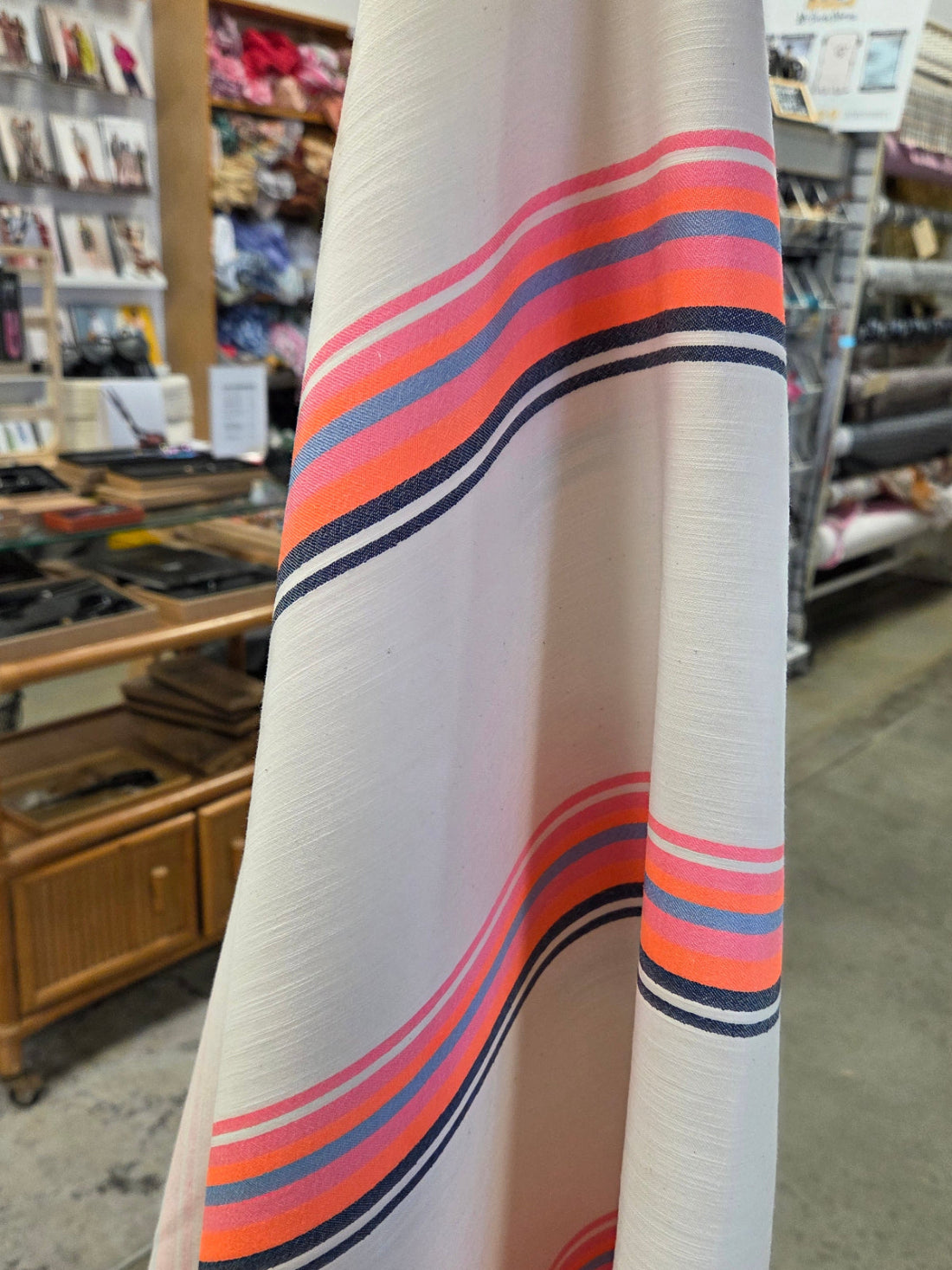 Roll of fabric with colorful stripes held in a store setting