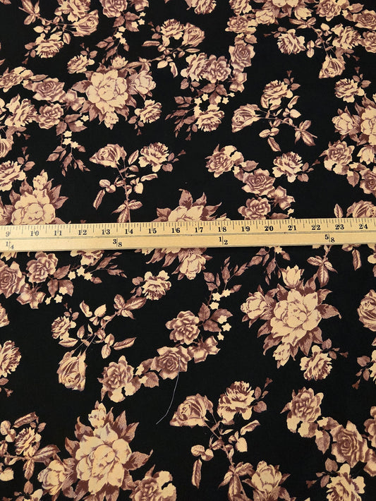 Black floral fabric with a vintage rose pattern in beige and brown, shown with a wooden ruler in the center for scale.