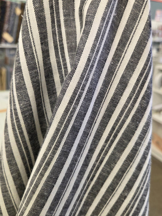 A close-up of a striped fabric, likely a shirt or garment, featuring vertical stripes in black, white, and gray.