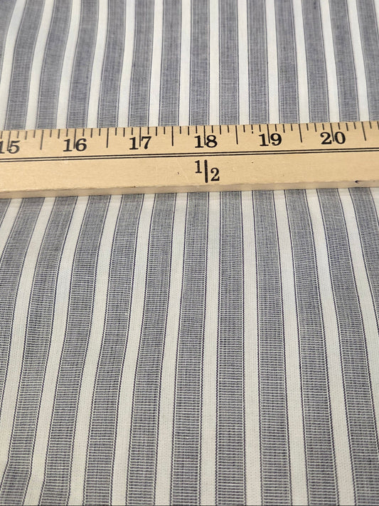 Blue and white vertically striped fabric with a wooden ruler laid horizontally for scale.