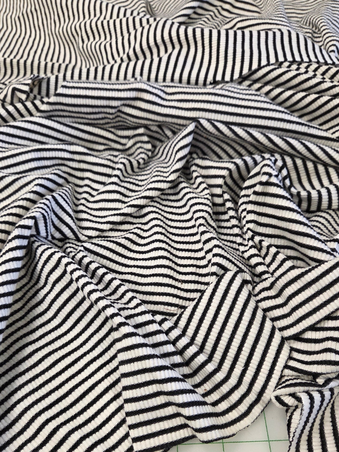 Black and white striped knit fabric draped on a white gridded cutting mat.