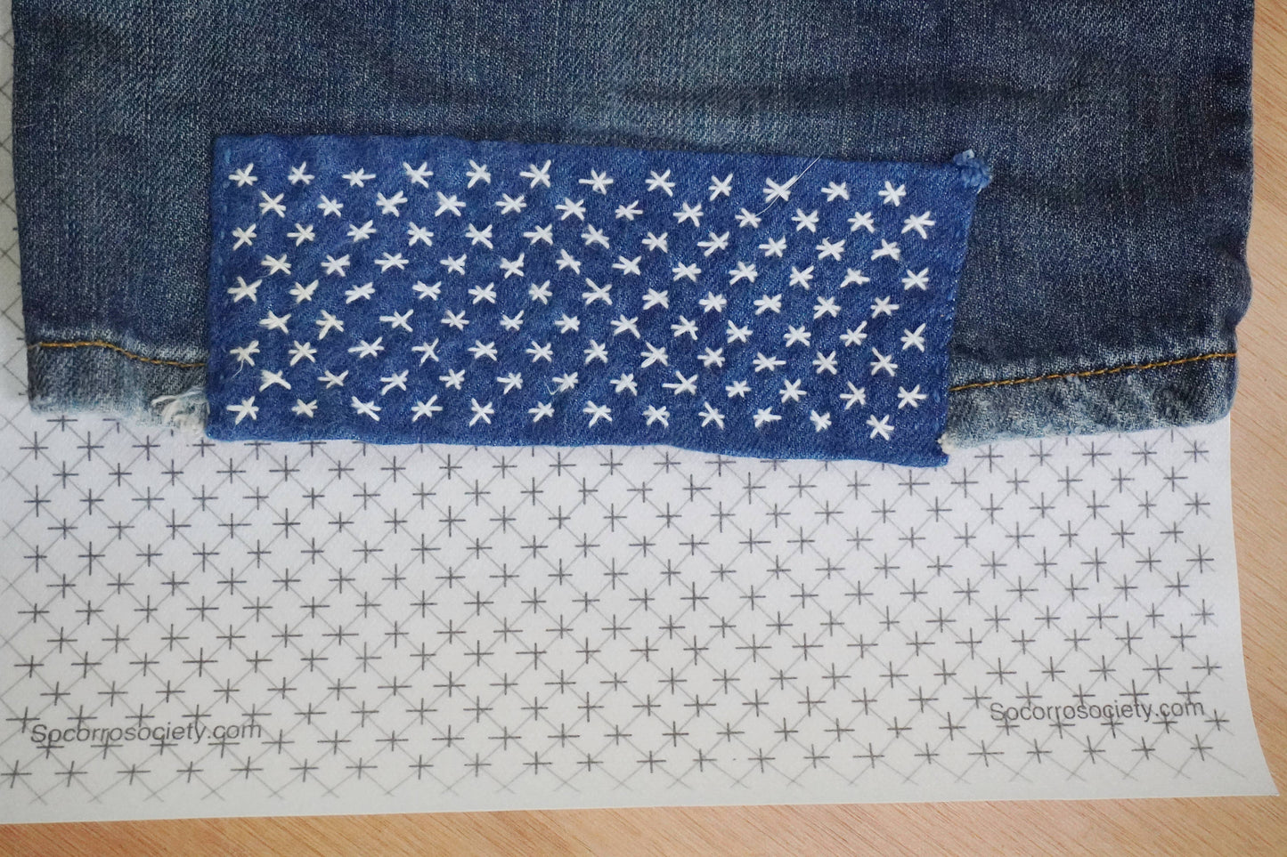 Patch of blue fabric with white star pattern on a denim background