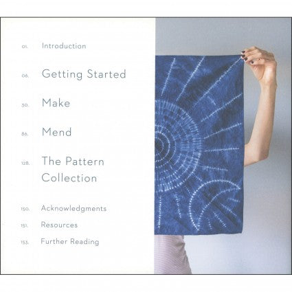 Book cover with a blue patterned fabric held by a hand on a gray background