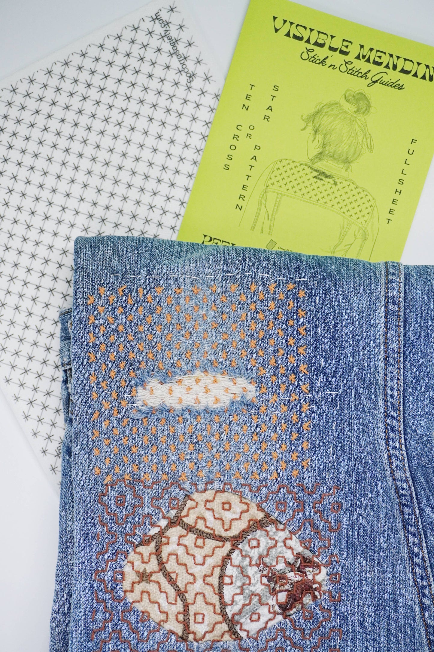 Blue denim fabric with embroidered bear design, next to a green pattern sheet titled 'Visible Mendin'.