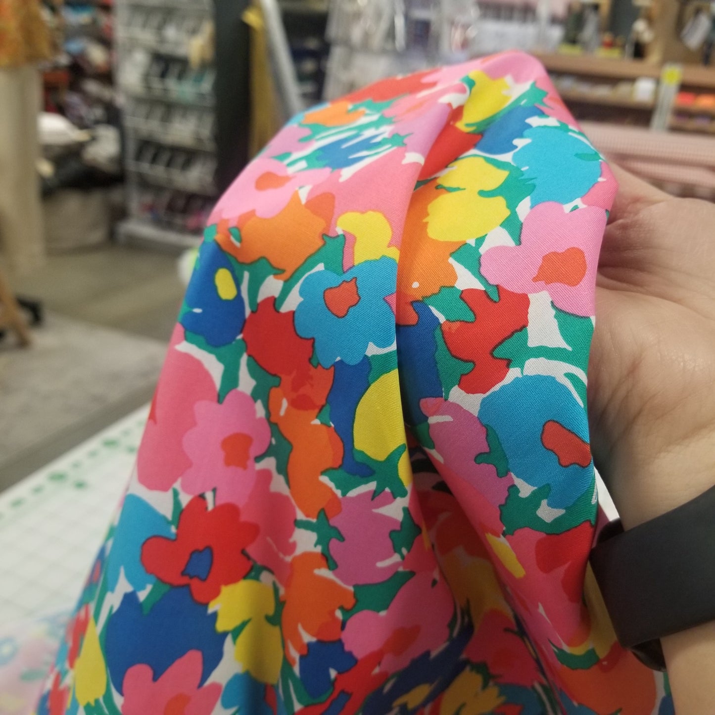 Colorful floral-patterned product held by a hand in an indoor setting