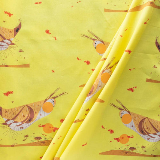 A bolt of fabric with a yellow background featuring a repeating pattern of birds and small motifs.