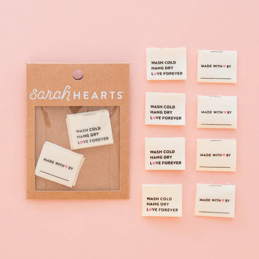 Pack of eight woven organic cotton labels with 'Sarah Hearts' branding, featuring text for washing and care instructions.
