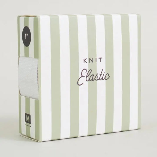A box of Knit Elastic yarn, featuring a white and sage green striped design. The front of the box displays the text 'KNIT Elastic' in black and gray, and a side window shows a white roll of elastic yarn.